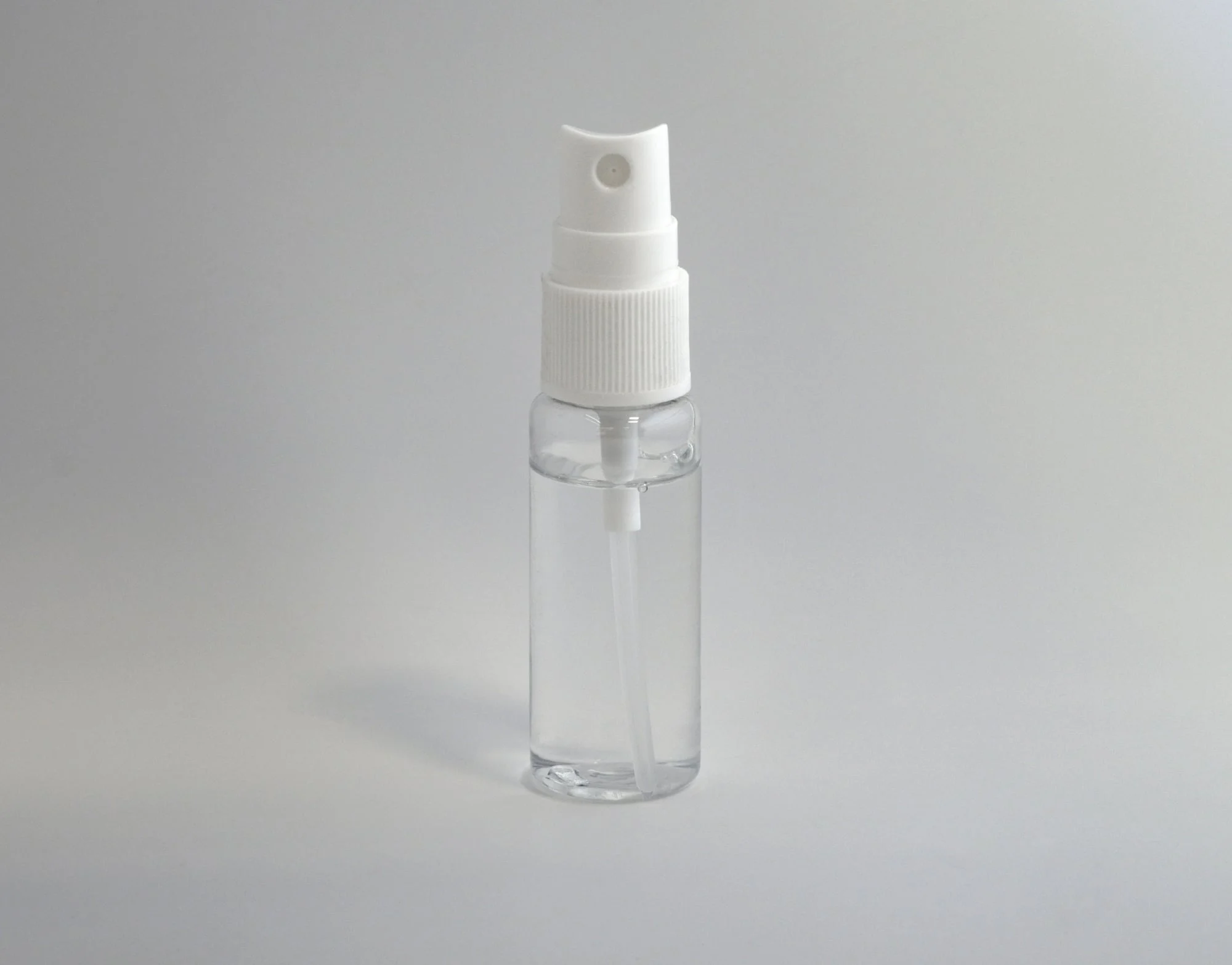A clear spray bottle with a white cap.