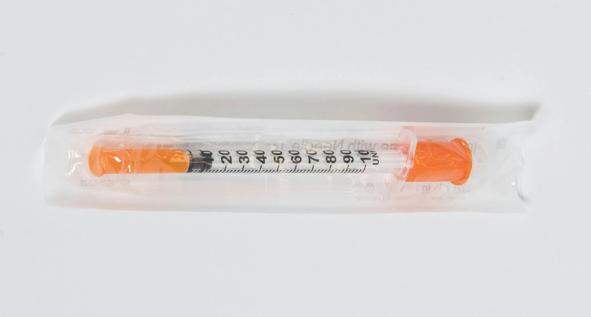 An insulin syringe in its sealed wrapper, marked from 0 to 100 units.