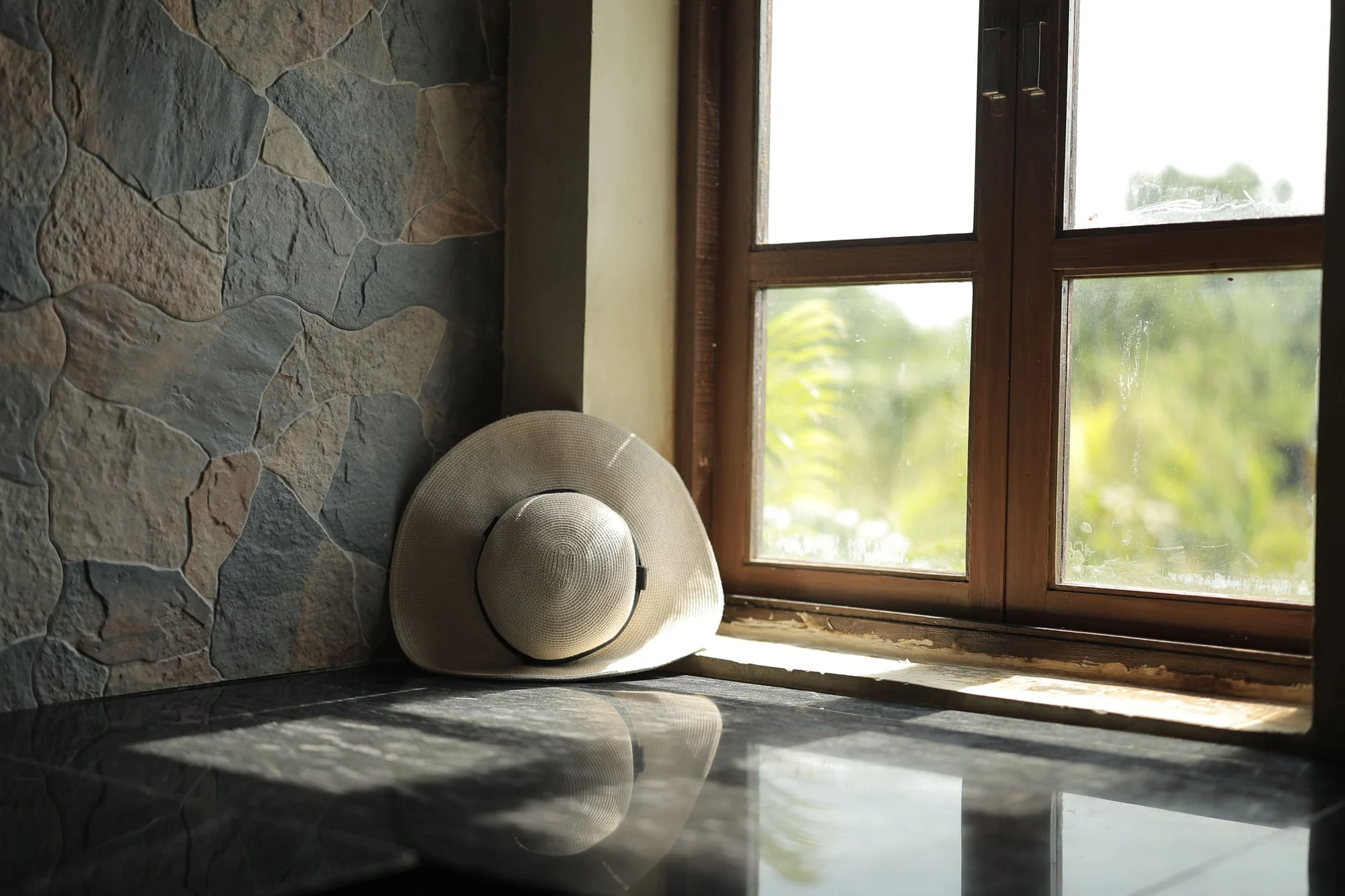 A straw hat by a sunny window.