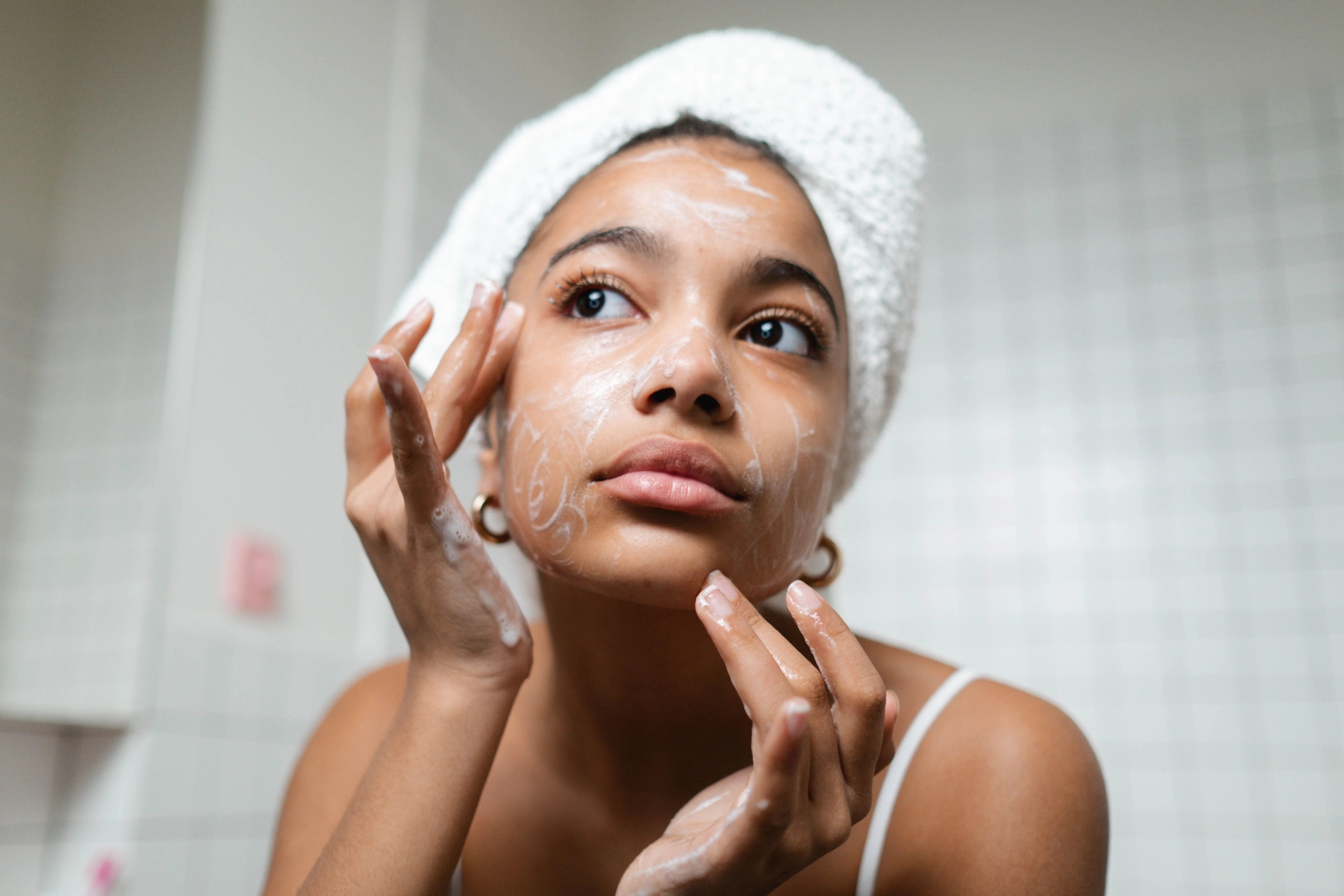 Woman applying cream with a towel wrapped on her head